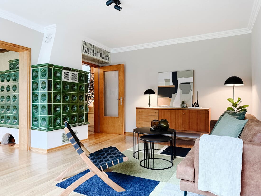 Wohnzimmer einer Erbimmobilie in Sailauf bei Aschaffenburg nach dem Home Staging mit modernem Einrichtungskonzept und grünem Kachelofen